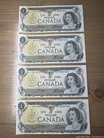 Four sequential 1973 Canadian one-dollar bills laid out on table