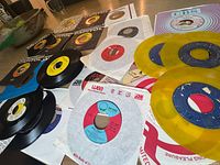 Group shot of assorted 7-inch singles with sleeves, two yellow vinyl discs visible