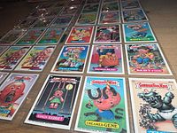 Overview of multiple Garbage Pail Kids cards in plastic sleeves on table