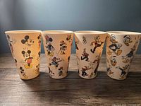 Front view of all four tumblers showing colorful, vintage Disney character prints: Mickey, Minnie, Donald, and Pluto.