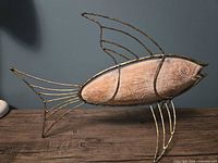 Side view of fish decor showing carved wooden body and speckled goldtone metal frame