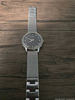 Front view of the ladies Guess watch showing the round face with CZ inlays and mesh band.