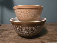 Side view showing stacked bowls with the brown Woodland pattern and white floral design