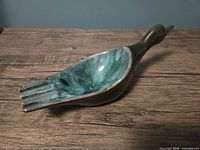 Top angle of vintage ceramic duck ashtray showing glaze colors and cigarette grooves.