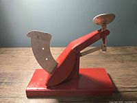 Front view of red metal egg grader with scale arm and pan
