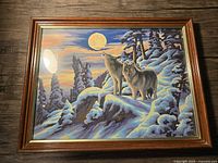 Front view of framed paint by numbers painting with wolves on a snowy mountain and full moon