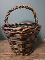 Front view of woven wicker basket with handle against a plain background.