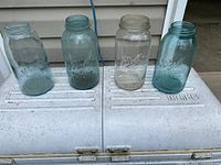 Four large embossed glass jars lined up