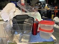 Group shot showing lunch bag, clear bins, red tumbler, food containers, thermos tops visible