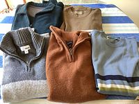 Group shot of all five sweaters laid out on surface