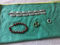 All five jewelry pieces: silver link bracelet, red bead bracelet, two rings, jade pendant