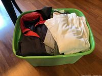 Green tote filled with mixed clothing items (jackets, shirts, etc.)