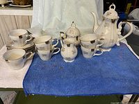 Full view of demitasse set showing teapot, sugar bowl, creamer, cups and saucers