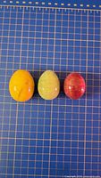 Three colored stone eggs on grid mat