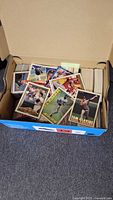 Open box with visible stacks of baseball cards and several cards spread on top showing player fronts