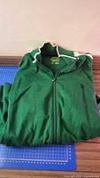 Folded green full-zip jacket on table