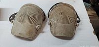 Top view of two beige knee pads with concentric circle pattern, showing outer shell with some dirt and wear.