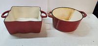 Photo showing two heavy vintage Bella ceramic pots, one square and one round, placed side by side with cream interiors and red exteriors