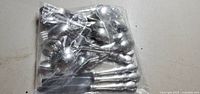 Clear plastic resealable bag filled with mixed steel utensils including several spoons and forks.