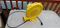 Yellow electric blower fan on a table with power cord extended.