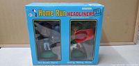 Front view of Home Run Headliners XL bobbleheads in blue box with two baseball player figures visible through clear windows.