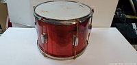 Red base drum on a white background showing front view with chrome hardware and white drum head.
