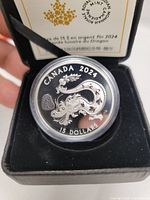 Reverse of coin showing dragon design and inscriptions within capsule inside box