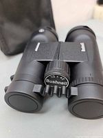 Front view showing focus knob with 10x42 marking and attached objective lens caps