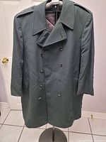 Full front view of dark green double-breasted coat on stand