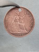 Reverse of 1967 one penny coin showing Britannia and drilled hole