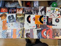 Wide view of all records laid on floor, showing quantity and mix of LPs and singles