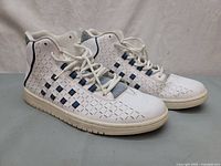 Side view of both sneakers showing geometric cutouts and blue underlay