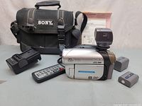 Camcorder front left with accessories and bag visible