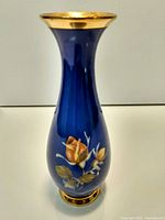 Full view of cobalt blue porcelain vase showing rose design, gold rim and base