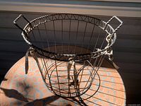 Overall view of dark gray steel wire basket with handles and fabric ties