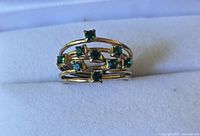 Front view showing gold tone bands and seven green stones