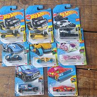 All eight Hot Wheels cars laid out on wooden surface