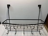 Front view of matte black wire over-door organizer showing basket, hooks, and door brackets