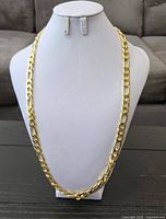 Full view of gold plated figaro chain on display bust