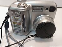 Front angled view of Nikon Coolpix 4300 with lens cap and wrist strap attached