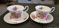 Both teacup and saucer sets side by side showing floral patterns and gold trim
