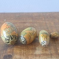 All four graduated map-themed eggs lined up on wood surface