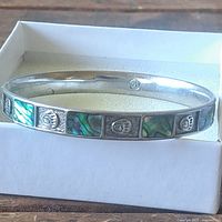 Full view of slip-on bangle in box showing abalone inlay and bear paw panels