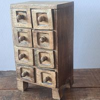 front left view of small wooden chest showing eight drawers and rustic wear