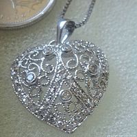 Close view of heart-shaped sterling filigree pendant showing pavé stone accents