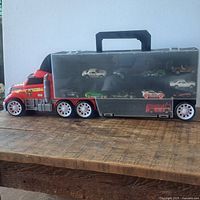 Overall view of semi-truck carrying case with clear door showing cars inside