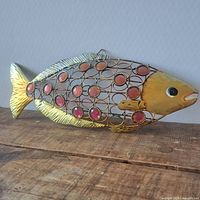 Full view of metal fish sculpture showing design, stones and color