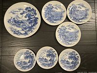 Top view of all seven blue and white Countryside pattern plates arranged on table