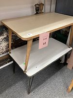 Photo showing two mid-century modern style side tables stacked, with the larger cream-topped table on top and smaller white-topped table below.