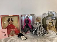 Four Barbie dolls together, including 2011 Holiday Barbie in original box, a doll in black and pink gown, a doll in zebra print and silver dress, and 1998 Christmas Magic Barbie in original box